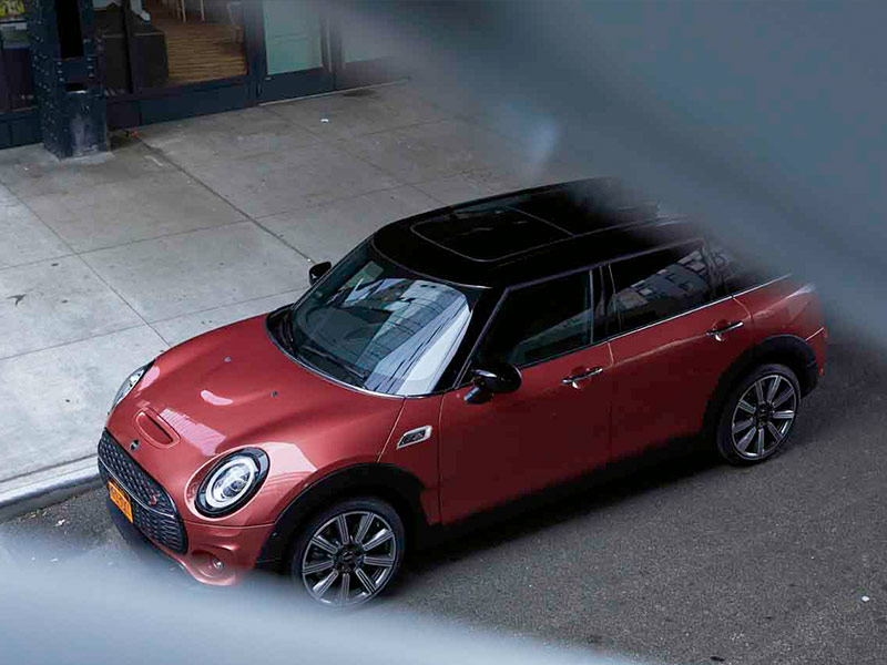 Roter MINI Clubman auf einer Straße neben einem Gehweg, aus erhöhter Perspektive fotografiert.