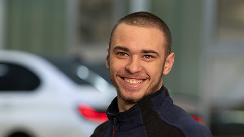 Ein Mann lächelt, Hintergrund unscharf mit einem Auto.